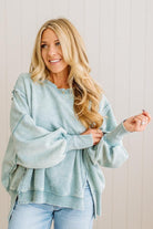 Woman wearing a light blue sweater and jeans against a neutral background