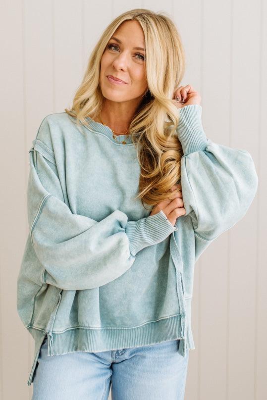 Woman wearing a light blue sweater and jeans against a plain background