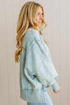 Woman wearing a light blue sweater against a beige wall