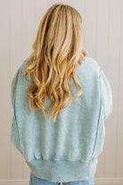 Person wearing a light blue sweatshirt with a neutral background