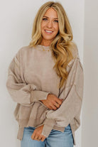 Woman wearing a beige sweater and blue jeans against a white background