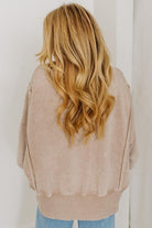 Person wearing a beige sweater with long, wavy blonde hair.