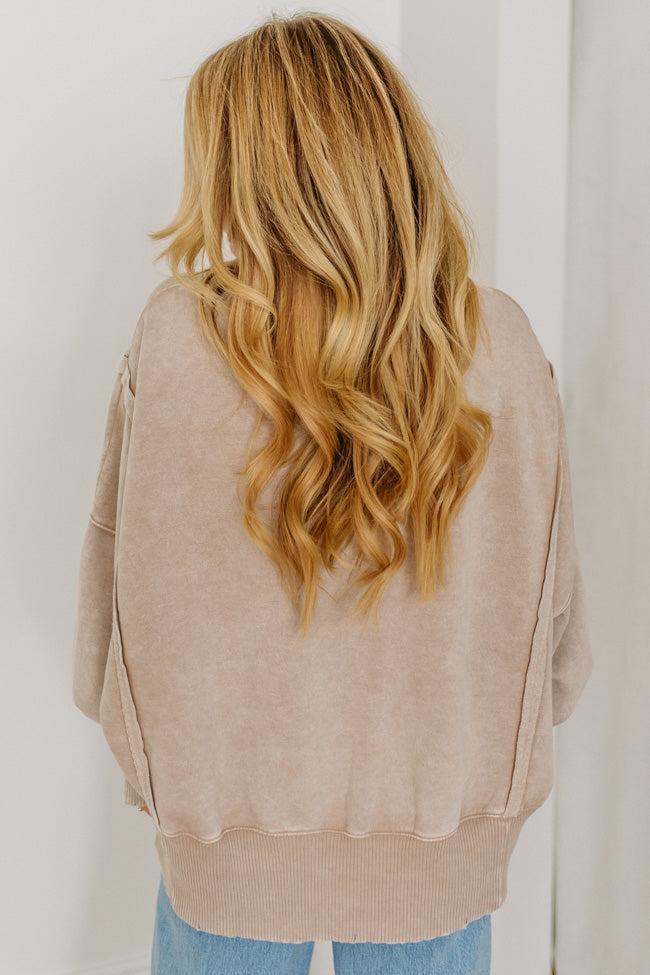 Person wearing a beige sweater with long, wavy blonde hair.