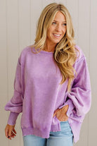 Woman wearing a purple sweatshirt with a neutral background