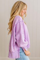 Woman wearing a purple oversized sweater against a neutral background
