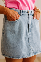 Person wearing a light blue denim skirt with a pink top.