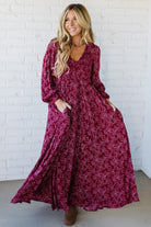 Blonde Woman Wearing a Smocked Floral Maxi Dress with Button Front and v-neckline in a deep wine red color.