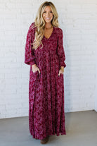 Blonde Woman Wearing a Smocked Floral Maxi Dress with Button Front and v-neckline in a deep wine red color.