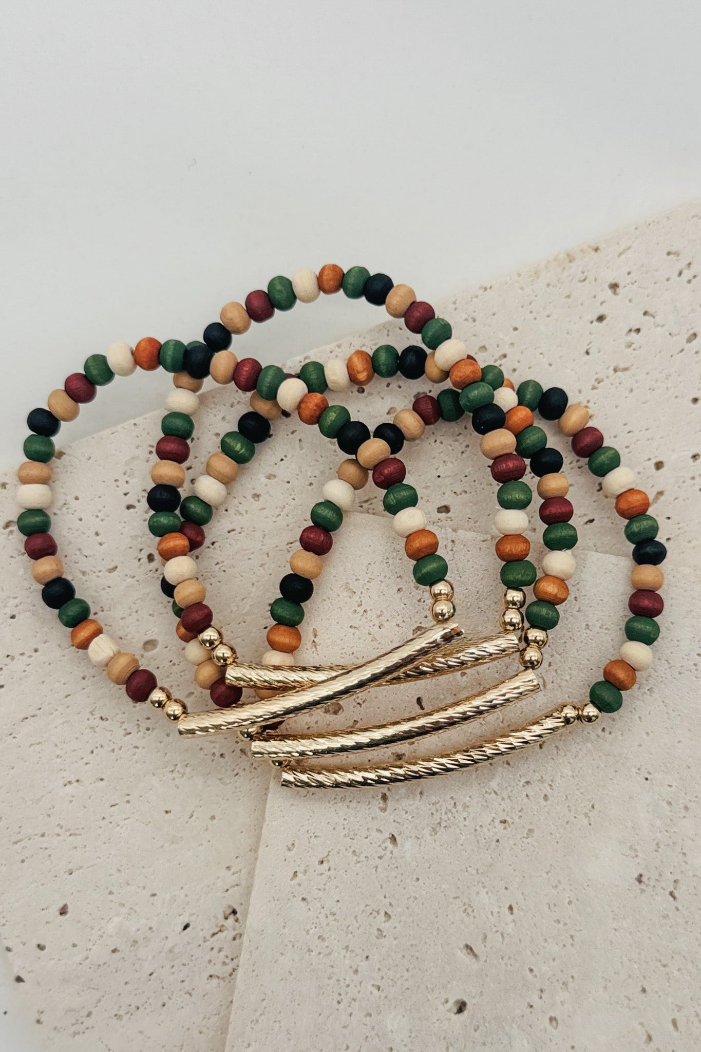 Multicolored beaded bracelets with gold accents on a textured surface