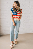 BLONDE WOMAN WEARING A WOVEN STAR AMERICAN FLAG THEME RIB BANDED SHORT SLEEVE SWEATER WITH MOCK NECKLINE.