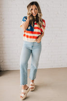 BLONDE WOMAN WEARING A WOVEN STAR AMERICAN FLAG THEME RIB BANDED SHORT SLEEVE SWEATER WITH MOCK NECKLINE.