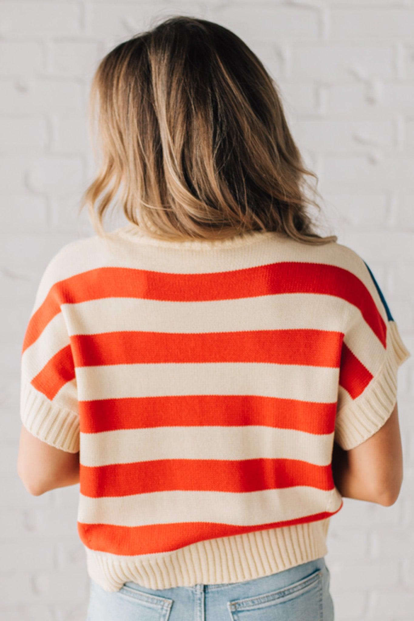 BLONDE WOMAN WEARING A WOVEN STAR AMERICAN FLAG THEME RIB BANDED SHORT SLEEVE SWEATER WITH MOCK NECKLINE.