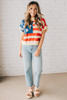 BLONDE WOMAN WEARING A WOVEN STAR AMERICAN FLAG THEME RIB BANDED SHORT SLEEVE SWEATER WITH MOCK NECKLINE.