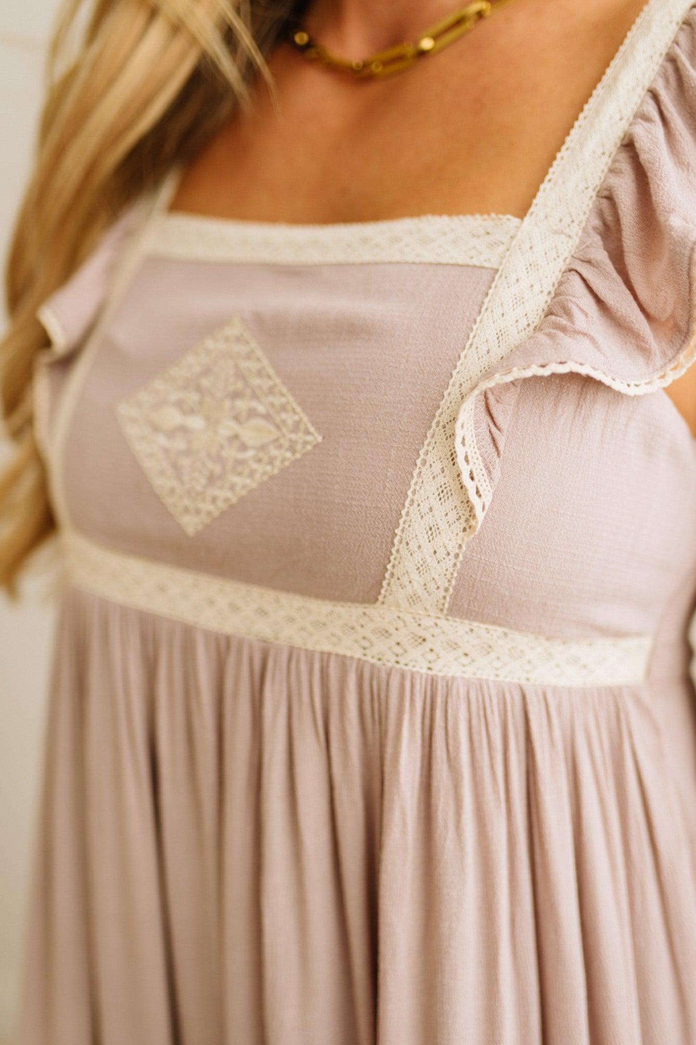 Close-up of a beige dress with lace details on a plain background