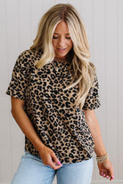 Woman wearing a leopard print shirt and light blue jeans against a plain background