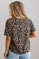 Person wearing a leopard print top and blue jeans against a light background