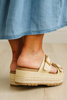 Close-up of a sandal with a platform sole worn with a denim skirt.