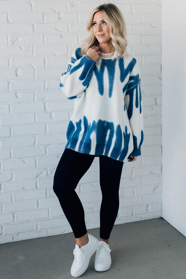 woman wearing an oversized sweater in a trendy ivory and blue graffiti print