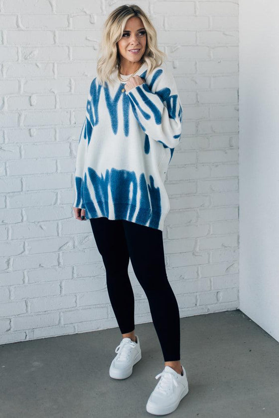 woman wearing an oversized sweater in a trendy ivory and blue graffiti print